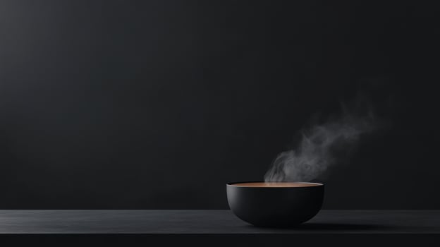 Dark studio shot of a bowl of steaming hot liquid photo
