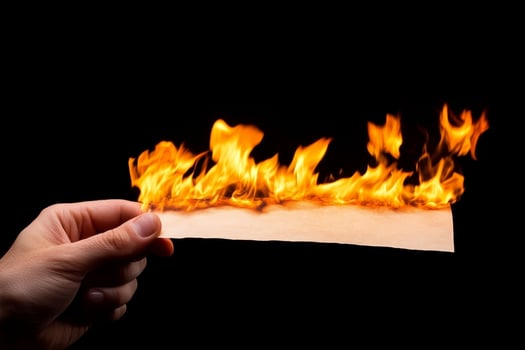 A person holding a piece of paper with fire on it photo