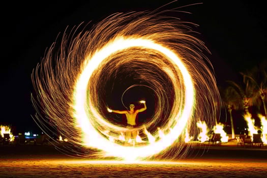 A man is spinning fire in a circle on the beach photo