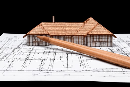 A house model and a pencil on a blueprint photo