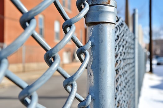 A chain link fence is shown in front of a building photo
