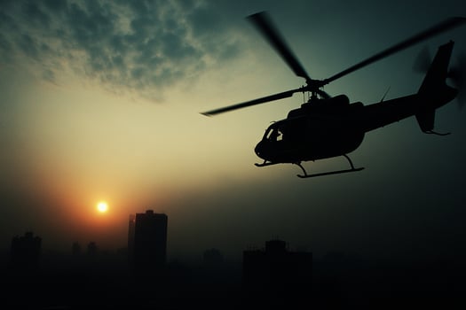 A helicopter flying over a city at sunset photo
