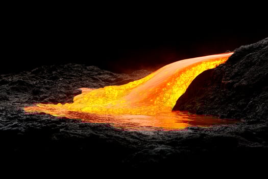 A lava flow is pouring out of a volcano photo