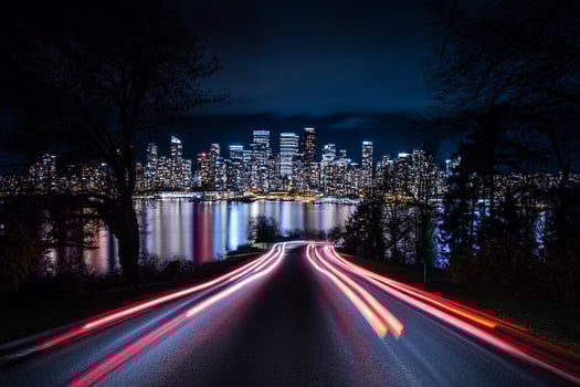 A city skyline at night with lights on the road photo