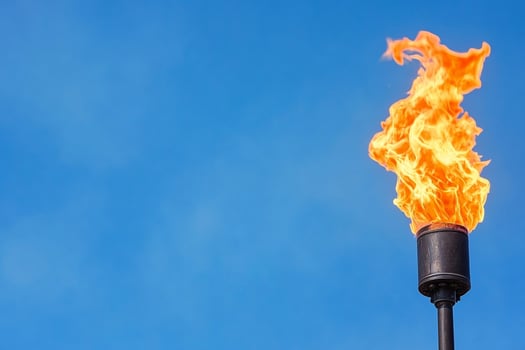 A flame is seen on a pole with a blue sky background photo