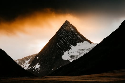 A mountain peak is silhouetted against a dark sky photo