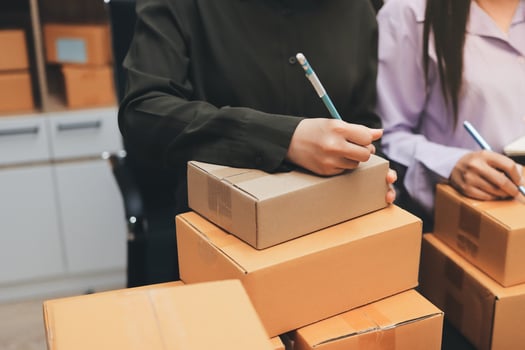 Two people are working on boxes in an office photo