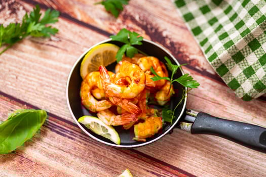 Appetizing seafood in a frying pan with lemon and herbs on a wooden photo