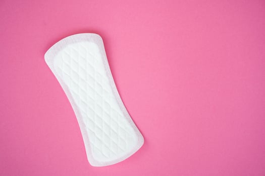 Single white sanitary pad isolated on a plain pink background. Suitable for topics related to feminine hygiene, menstruation, and personal care products. photo