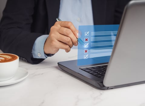 Businessman holding a pen and writing a checkmark symbol on a document management system or DMS on a virtual screen photo