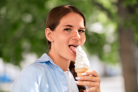 Icecream Woman Licking. Outdoors summer day, girl enjoys sweet treat to cool down because it's hot. photo