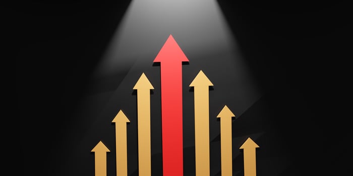 Leadership and success symbolized by a red arrow rising among golden arrows under a spotlight, representing growth, direction, and outstanding achievement. photo