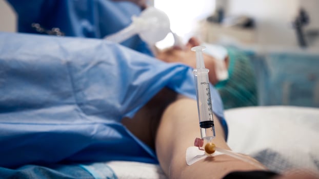 Patient receiving medical treatment in a clinical setting, with a syringe inserted into the arm, showcasing healthcare procedures and sterile environment photo