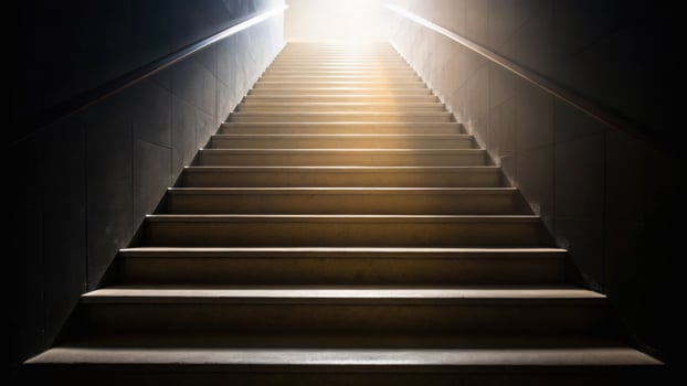 A dimly lit staircase leads upward to a bright light, symbolizing a journey from darkness to illumination or hope. photo