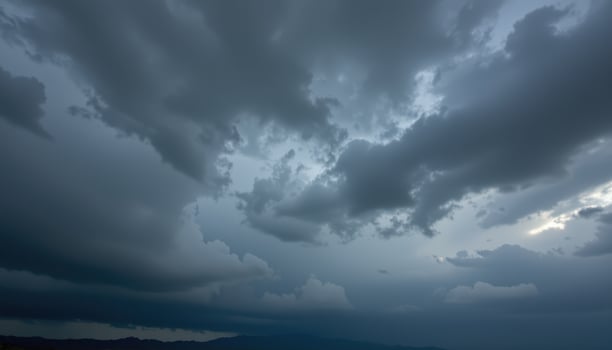 Dark dramatic storm clouds gather over distant mountains under a dim sky photo