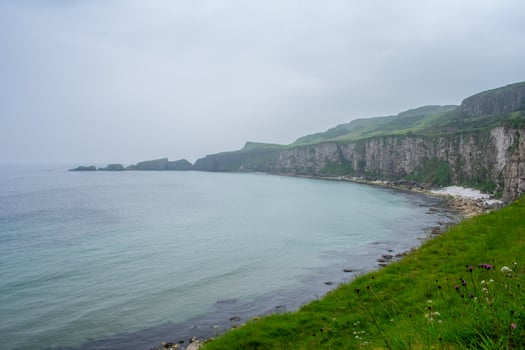 Cliffs, green water on Coast of Atlantic Ocean. Carrick a Rede Rope Bridge, Ballintoy, Northern Ireland. Beautiful Landscape and rock formation photo