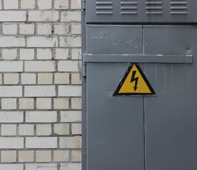 High Voltage Sign On A Steel Door On A White Brick Wall Texture Background photo