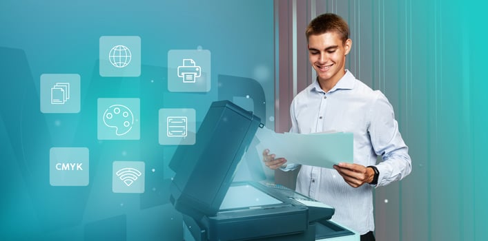 Young man operating a multifunction printer in a modern office and reviewing printed documents with satisfaction photo