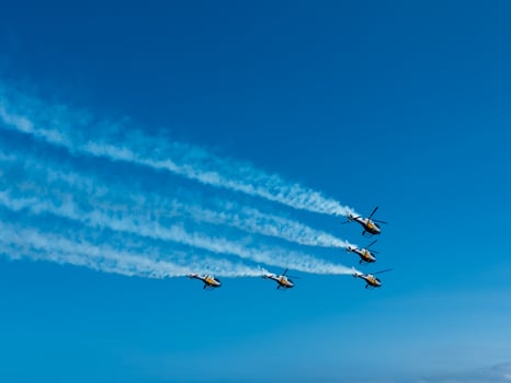 Gijon Air Festival. July 27, 2025. Spain, Gijon. Aerobatic helicopter formation in clear blue sky with smoke trails photo