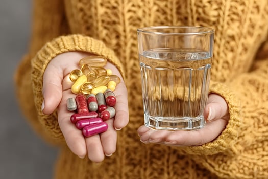 Woman holding pills and glass of water for daily vitamins photo