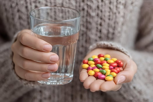 Woman holding colorful medicine and glass of water photo