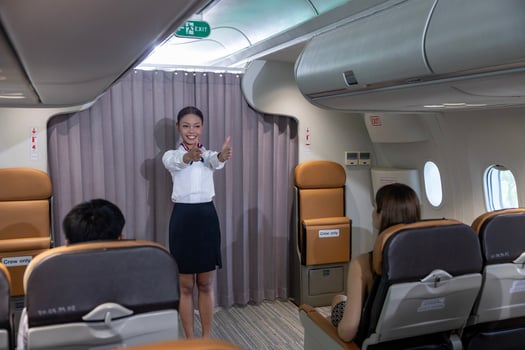 African flight attendant is demonstrating safety procedure showing emergency exit before taking off inside airplane for cabin crew and airline business photo