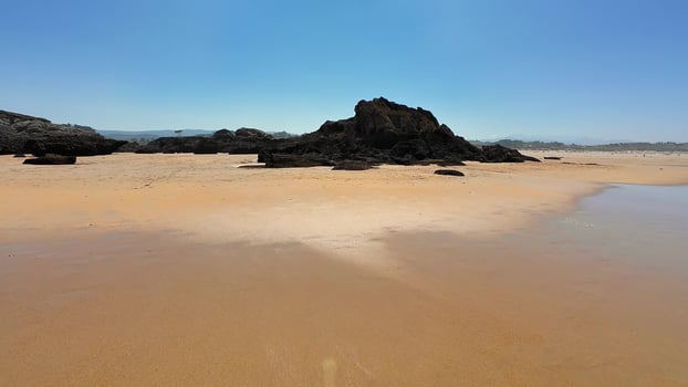 A serene and tranquil beach landscape adorned with rocks and featuring crystal clear skies photo