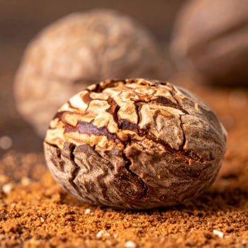 Fragrant Nutmeg Seeds Close up on Brown Surface with Detailed Texture and Aroma photo