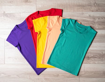 Assorted T Shirts Neatly Folded on Wooden Background in Studio Lighting Flat Lay photo