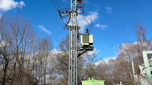 A utility pole supporting a transformer stands tall against a vibrant blue sky backdrop photo