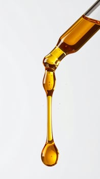 Golden Liquid Dripping from Glass Dropper on White Background in Vertical Format photo