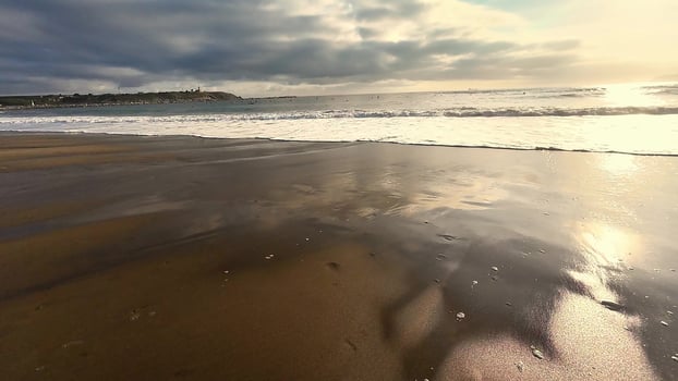 A breathtaking and serene beach sunset scene accompanied by gentle, soothing waves photo