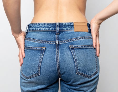 Woman In Blue Acid Wash Jeans Posing With Hands On Her Waist Indoors photo