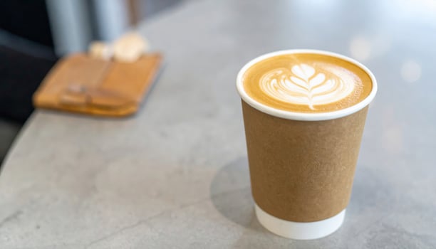Close Up Latte Art Coffee in Take Away Cup on Gray Table with Wallet photo