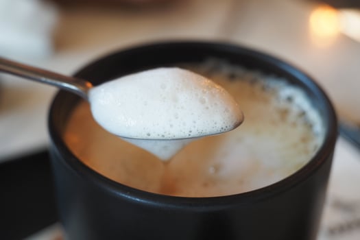 Coffee with foam served in a black mug at a cozy cafe photo