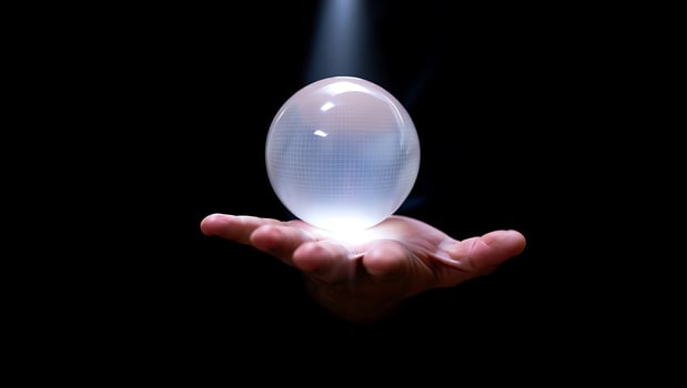 Mystical Crystal Ball held aloft in a Hand bathed in Ethereal Light against a Black Background representing Future Insight and Fortune Telling photo
