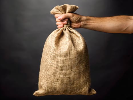 Close Up of a Hand Holding a Burlap Sack Against a Dark Background photo