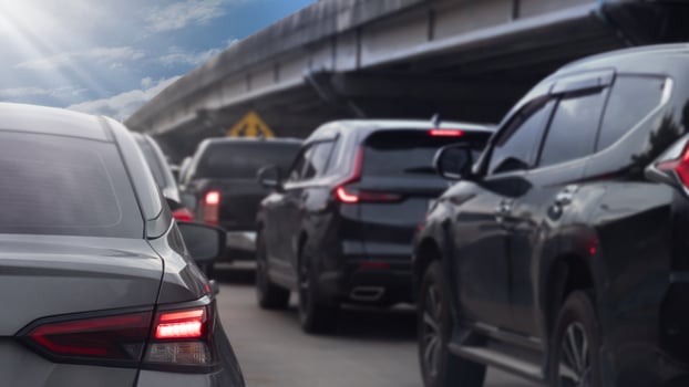 Rear side of gray car and turn on brake light. Traffic is congested with many cars queuing up. Background of concrete bridgeunder blue sky. photo