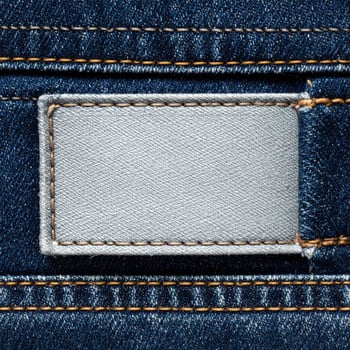 Macro Shot of Blue Denim Jeans with a Blank Grey Label and Orange Stitching photo