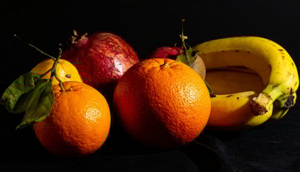 Dramatic Still Life Arrangement with Pomegranate Oranges Banana Against Dark Background photo