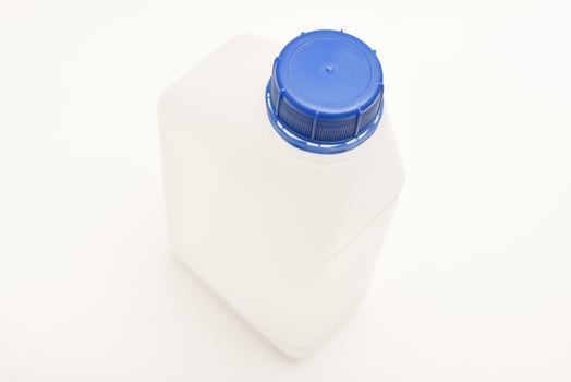 A white plastic can with a blue top. A small plastic canister. A container with liquid. photo