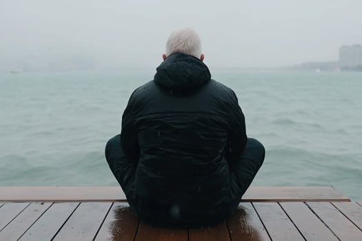 A man sitting on a dock looking out over the water photo