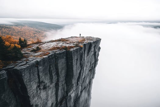 A man standing on the edge of a cliff in the fog photo