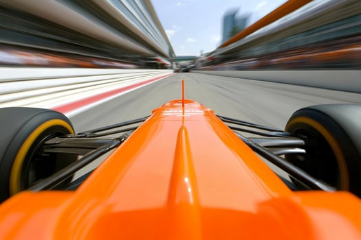 An orange racing car drives down a track photo