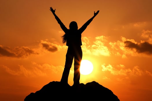 A woman standing on top of a mountain with her arms raised photo