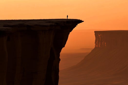 A lone person stands on the edge of a cliff photo
