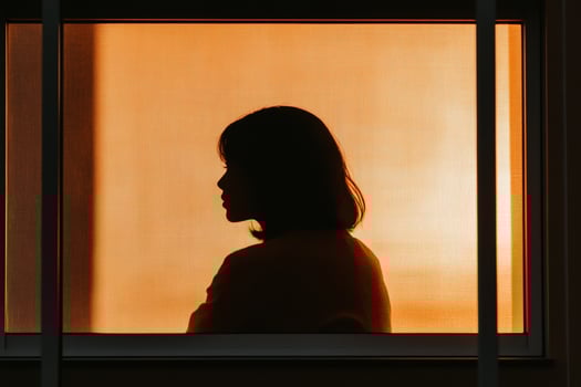 Silhouette of a woman looking out a window photo