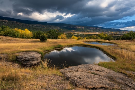 A small pond in a field with a mountain in the background photo