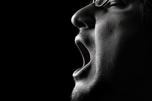 A man with glasses and a black background is screaming photo