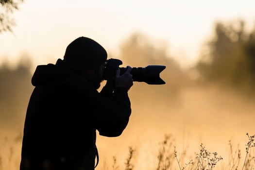A photographer taking a photo of a foggy field